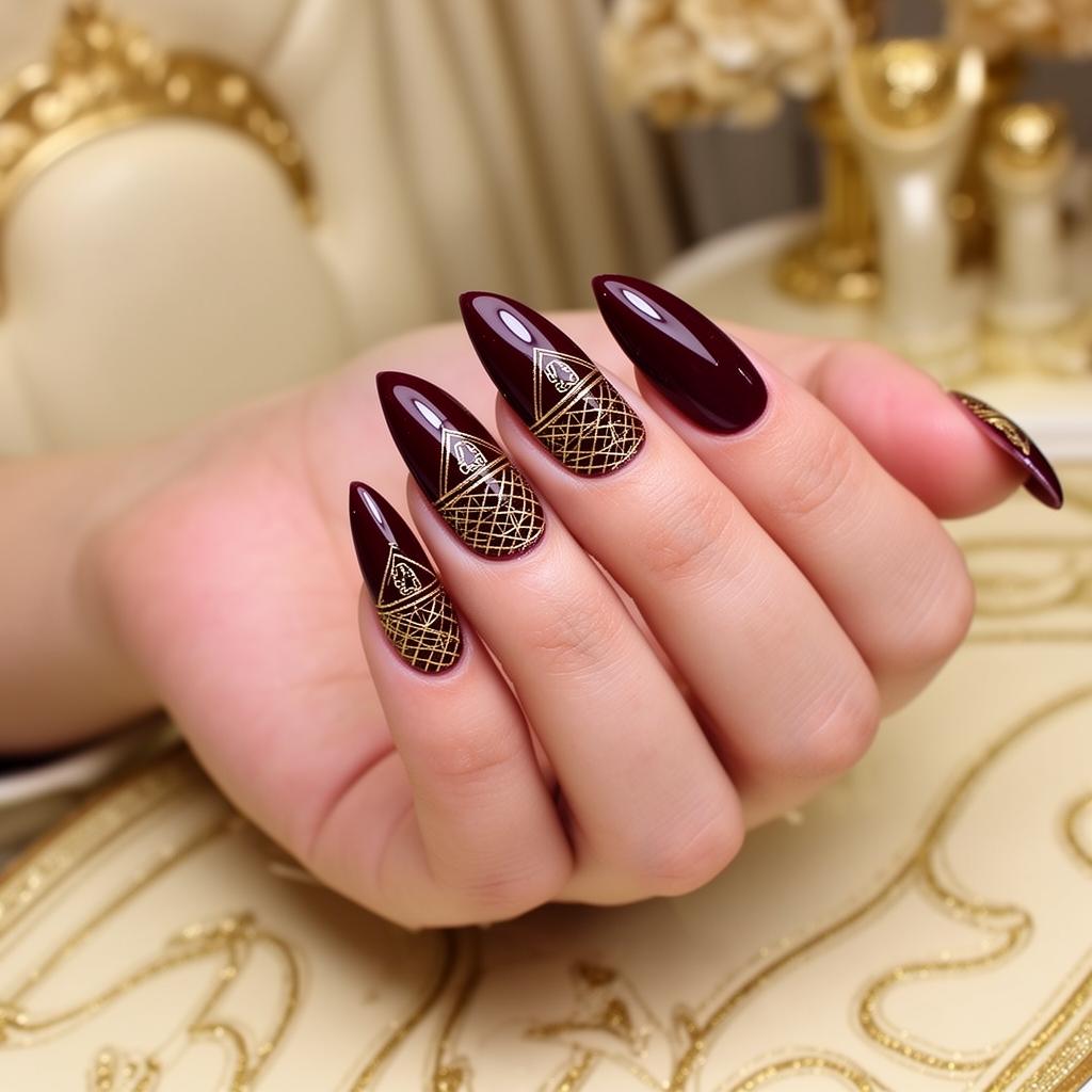 Deep burgundy nails with intricate gold patterns